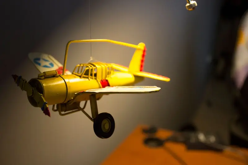 Close-up of a vivid yellow model airplane hanging indoors, capturing motion and detail