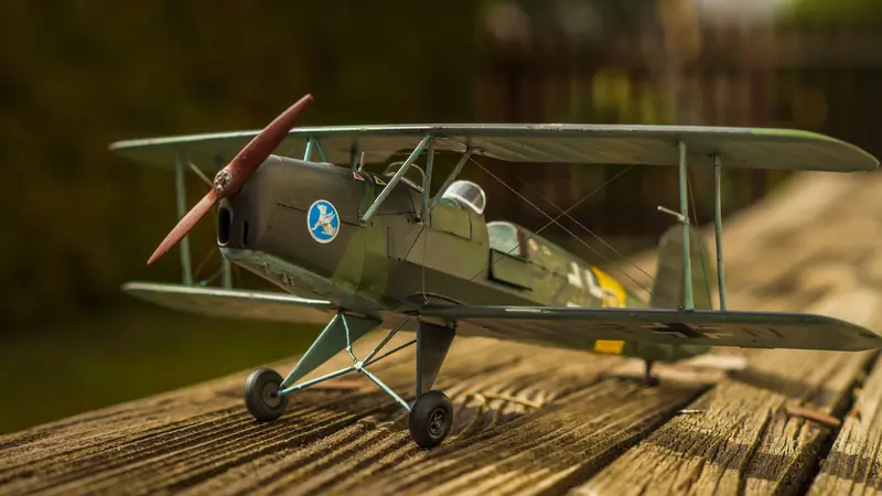 Close-up of a vintage biplane model with a propeller on a wooden surface outdoors