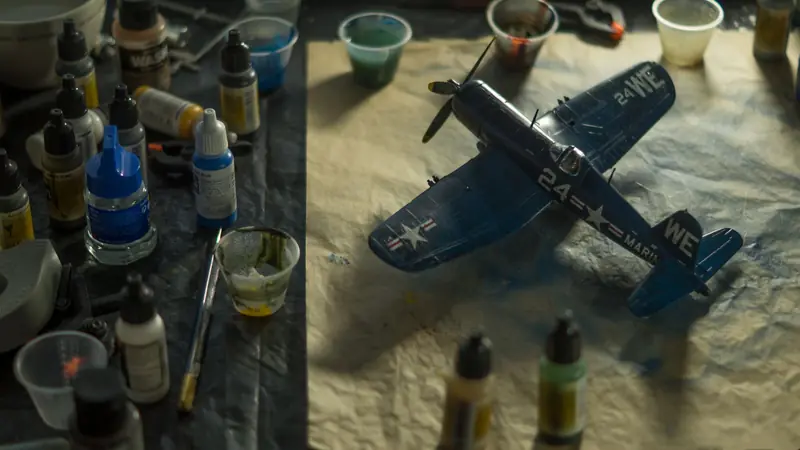 A model airplane surrounded by paints and brushes on a creative workspace