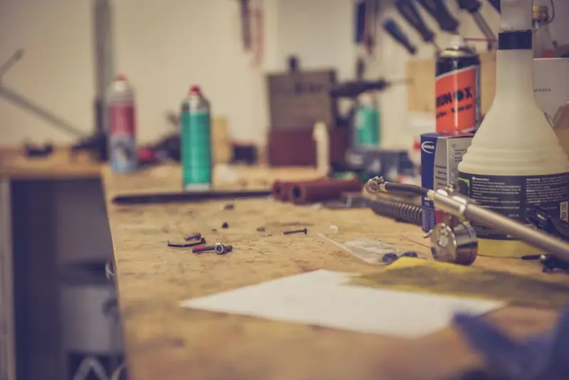 A cluttered workbench in a workshop with various tools and materials for maintenance