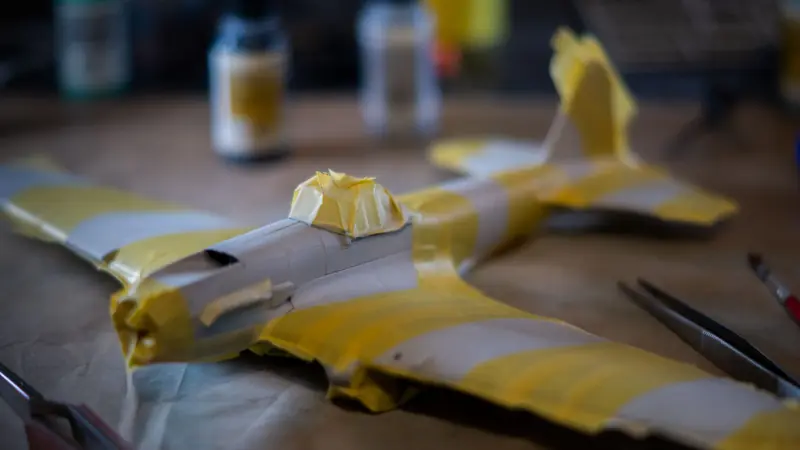 Close-up of a plastic model airplane with masking tape on a crafting table