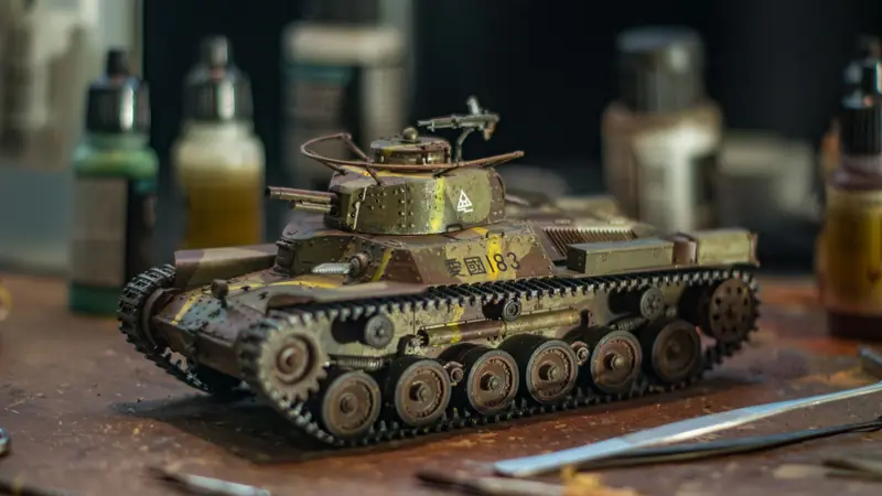 Close-up of a detailed model tank on a crafting workspace with paint bottles in the background