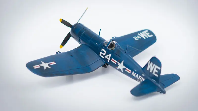 Close-up of a navy blue model airplane with military markings on a white background