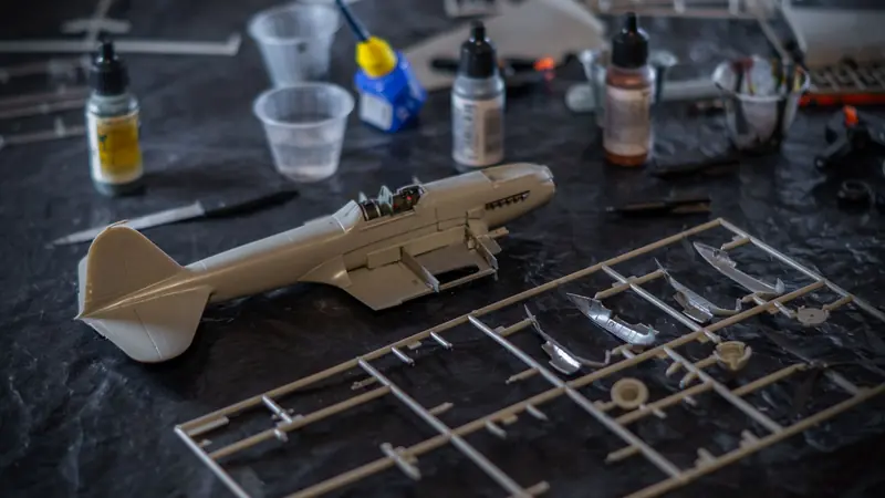 Detailed view of an assembly workspace for a scale model airplane with tools and paint bottles